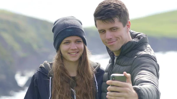 Young couple stands at the waterfront and takes a selfie — Stock Photo, Image