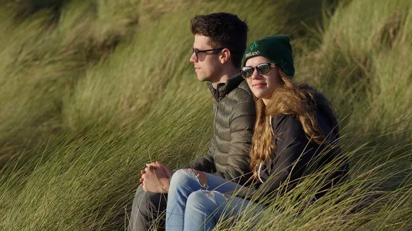 Szczęśliwa para siedzi w trawie reed na nabrzeżu — Zdjęcie stockowe