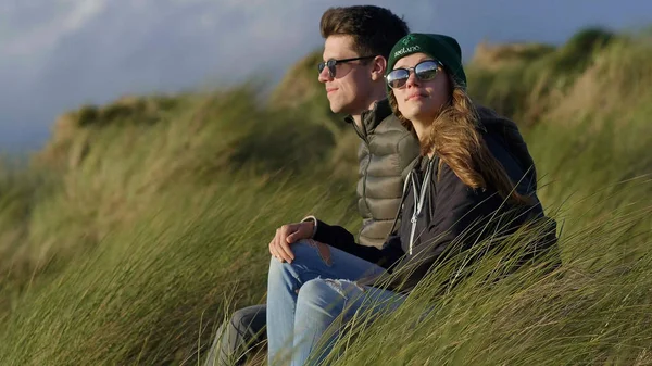 Szczęśliwa para relaksuje się w oceanie siedząc w trawa trzcina — Zdjęcie stockowe