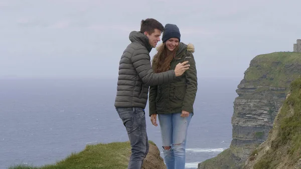 Young couple takes photos at the Cliffs of Moher — Stock Photo, Image