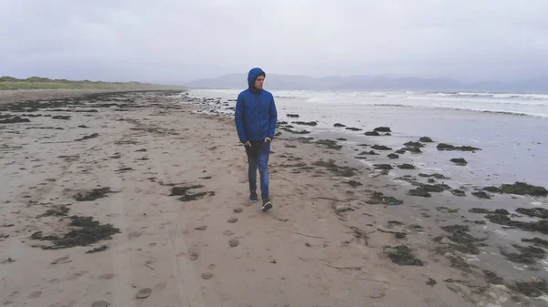 Młody człowiek idzie na pustej plaży wieczorem — Zdjęcie stockowe