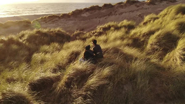 Vista aérea sobre una joven pareja sentada en la playa al atardecer — Foto de Stock