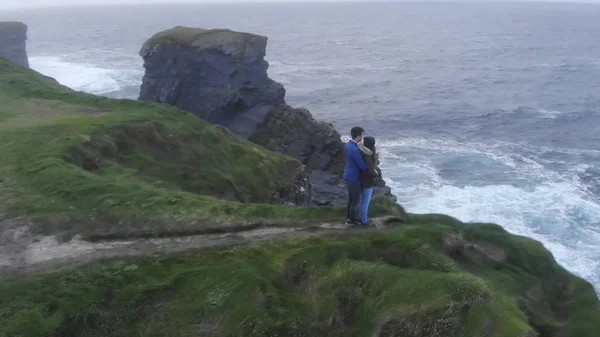 Young couple walks to the edge of a cliff at the Irish west coast — Stock Photo, Image