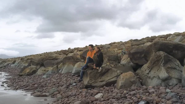 Dwóch przyjaciół siedzieć na skale i patrzeć na ocean — Zdjęcie stockowe
