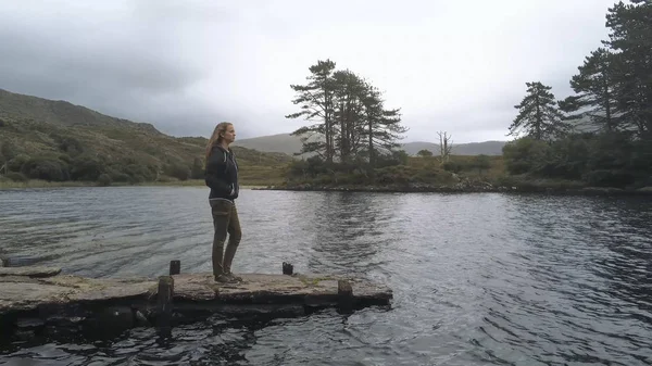 Chica joven se para en un muelle en un lago maravilloso en Irlanda — Foto de Stock