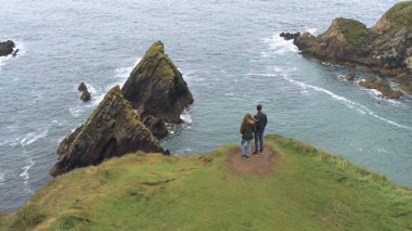 Genç çift Dunquin Pier İrlanda üzerinden manzarasının tadını çıkarın