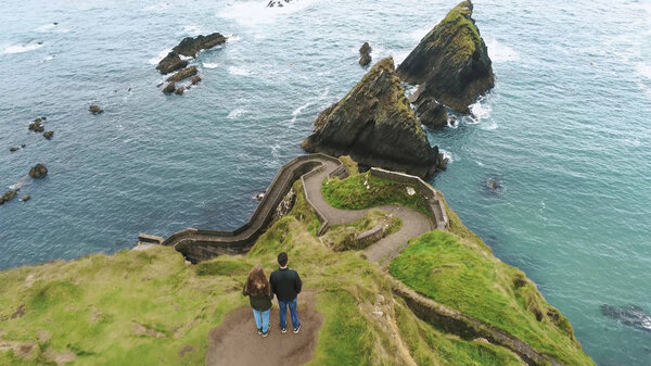 Young couple stands on the top of Dunquin Pier in Ireland