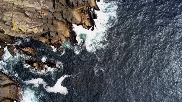 Deep blue ocean water and steep cliffs from above