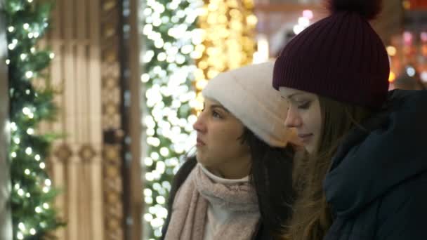 Dwie dziewczyny w Nowym Jorku patrzeć na Boże Narodzenie udekorowane sklep windows — Wideo stockowe