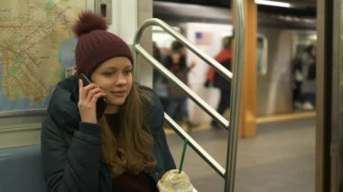 Genç kadın bir telefon bir New York metro treninin alır.