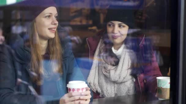 Два друга пьют кофе в кафе с видом на улицу — стоковое видео