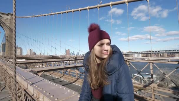 Mooie jongedame ontspant op Brooklyn Bridge terwijl u geniet van de prachtig uitzicht — Stockvideo