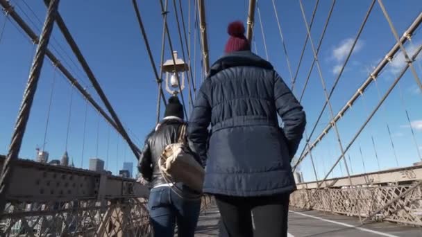 二人の女の子がニューヨークの有名なブルックリン橋を渡って歩く — ストック動画