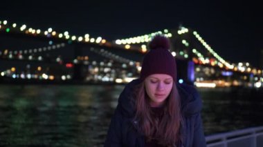 Genç kadın Brooklyn Köprüsü'nün New York gece oturur.