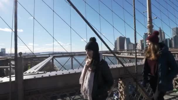 Two girls walk over the famous Brooklyn Bridge in New York — Stock Video