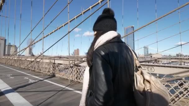 Młoda kobieta w Nowym Jorku podchodzi Brooklyn Bridge w słoneczny dzień — Wideo stockowe