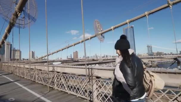 Young woman in New York walks over Brooklyn Bridge on a sunny day — Stock Video