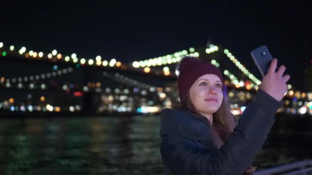 Girl takes a selfie photo at Brooklyn Bridge by night — Stock Video