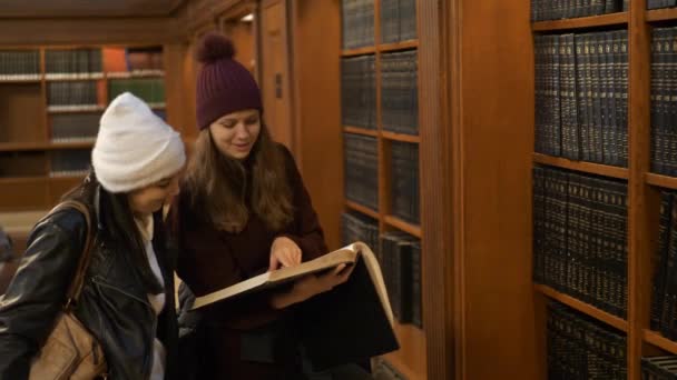 Dos mujeres investigando en una biblioteca — Vídeos de Stock