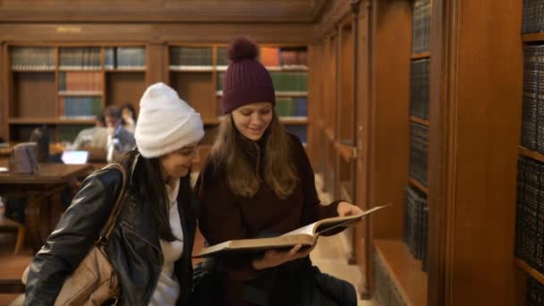 Duas mulheres fazendo pesquisa em uma biblioteca — Vídeo de Stock