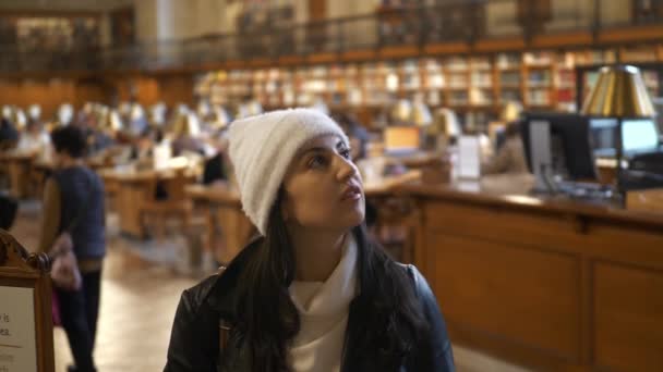 Νεαρή γυναίκα επισκέπτεται μια δημόσια βιβλιοθήκη — Αρχείο Βίντεο