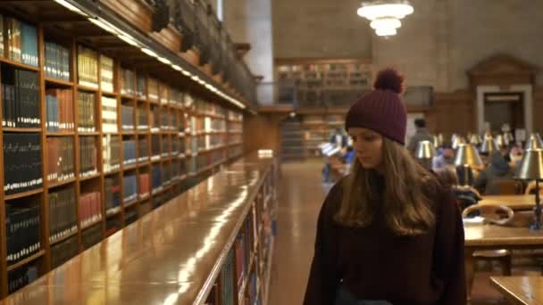 Jonge vrouw in een bibliotheek voor het bestuderen van — Stockvideo