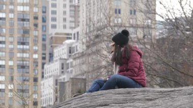 Genç kadın bir kayaya, New York Central Park rahatlatır