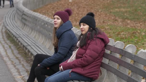 Två flickor i Central Park New York sitta på en bänk att slappna av — Stockvideo