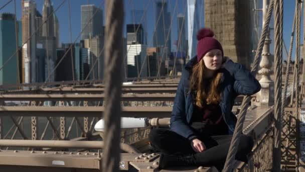 Piękna dziewczyna na Brooklyn Bridge cieszy się słoneczny dzień relaksując się — Wideo stockowe