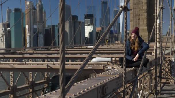 Menina jovem e imprudente senta-se na borda da Brooklyn Bridge New York — Vídeo de Stock