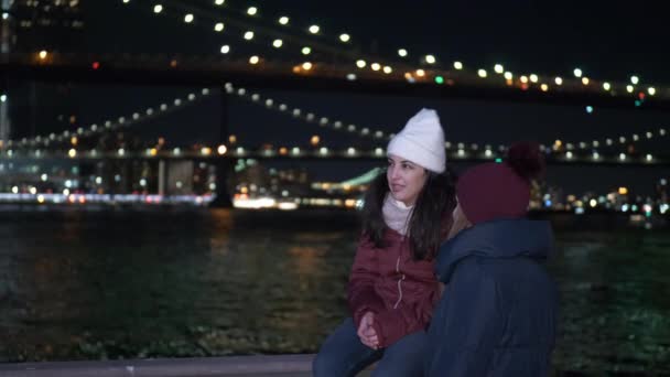 Dos chicas exploran Nueva York de noche aquí en Brooklyn Bridge — Vídeo de stock