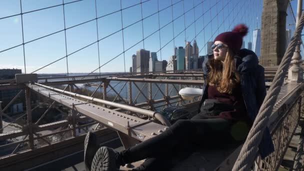 Menina jovem e imprudente senta-se na borda da Brooklyn Bridge New York — Vídeo de Stock