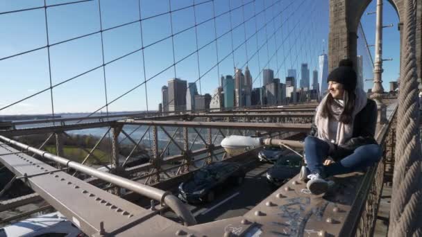 Młoda piękna kobieta na Brooklyn Bridge Nowy Jork cieszy się wspaniały dzień słoneczny — Wideo stockowe