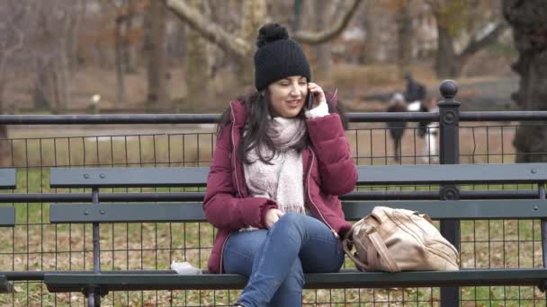 Odbieranie połączenia telefonicznego, siedząc na ławce w Central Park w Nowym Jorku — Wideo stockowe