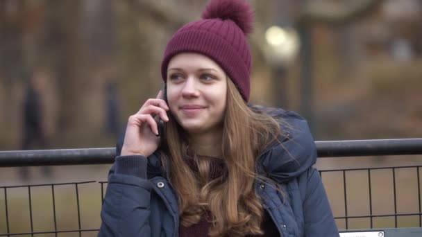 Беручи телефонний дзвінок, сидячи на лавці в центральному парку Нью-Йорка — стокове відео