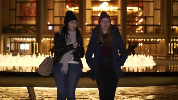 Dos chicas tienen una noche increíble en Nueva York mientras están sentadas en una fuente — Vídeos de Stock