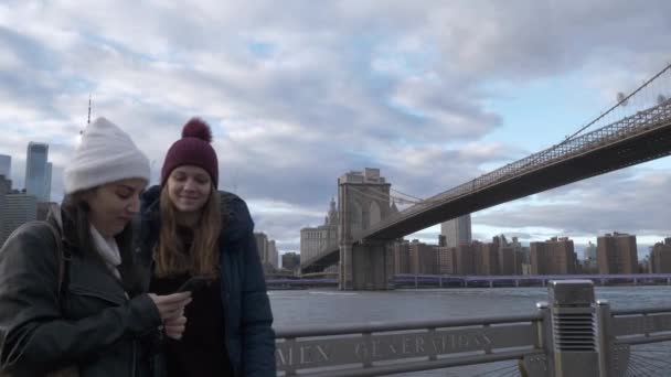 두 젊은 여성이 뉴욕 브루클린 다리에서 일반적인 스카이 라인 따라 산책 — 비디오