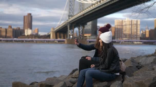 Zwei mädchen sitzen an der manhattan bridge und genießen ihren sightseeing trip nach new york — Stockvideo