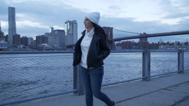 Mujer joven camina por el maravilloso horizonte de Manhattan por la noche — Vídeos de Stock