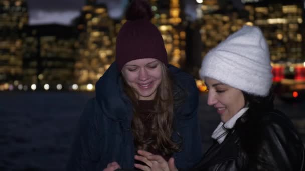 Duas garotas desfrutam de uma noite maravilhosa em Nova York em frente ao horizonte de Manhattan — Vídeo de Stock