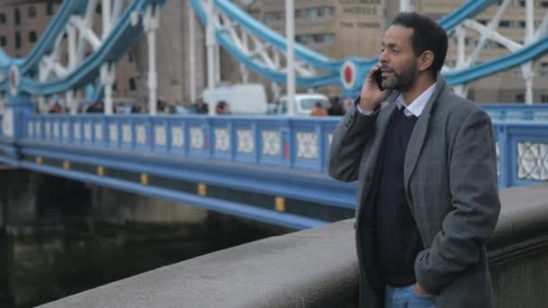 A londoni fekete üzletember veszi egy telefonhívást a Tower Bridge — Stock videók