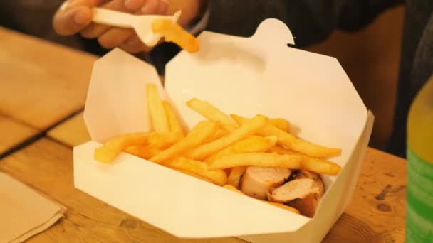 Homem em um restaurante come salsicha com batatas fritas — Vídeo de Stock
