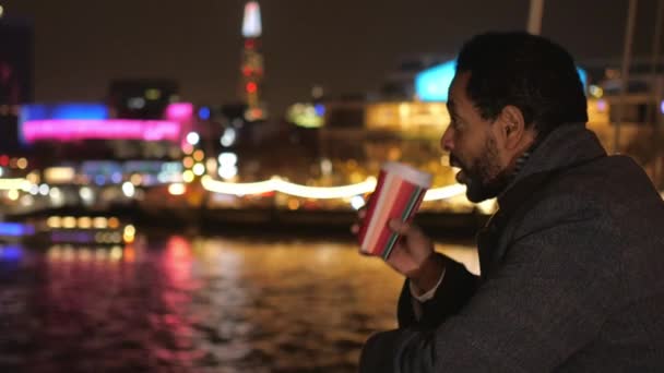 Hombre bebe café en un puente en Londres y disfruta de las luces de la ciudad por la noche — Vídeo de stock