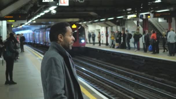 Zwarte man wacht op de trein op station van de metro van Londen aan — Stockvideo