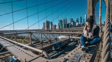 Genç güzel kadın üzerinde Brooklyn Köprüsü'nün New York güzel bir güneşli gün sahiptir