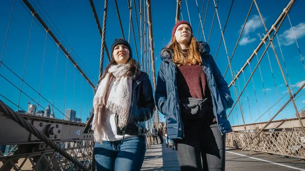 Zwei mädchen gehen über die berühmte brooklyn bridge in new york — Stockfoto