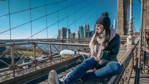 Chica joven e imprudente se sienta en el borde del puente de Brooklyn Nueva York — Foto de Stock