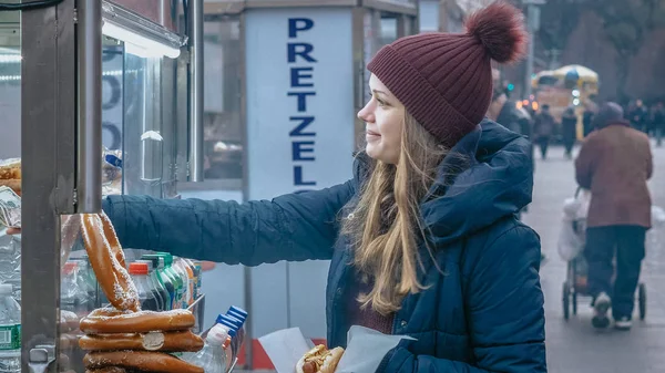 Молодая женщина покупает хот-дог на улицах Нью-Йорка — стоковое фото
