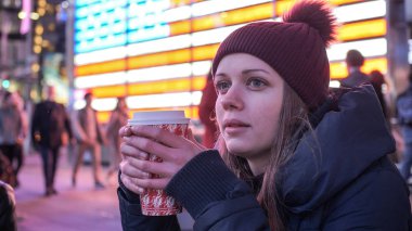 Genç kadın, New York sokaklarında kahve içer