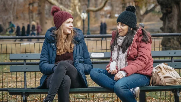 Due ragazze si siedono su una panchina di Central Park a godersi il loro tempo a New York — Foto Stock